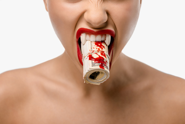 cropped shot of girl with vampire fangs holding rolled dollars with blood in mouth isolated on white - Photo, Image