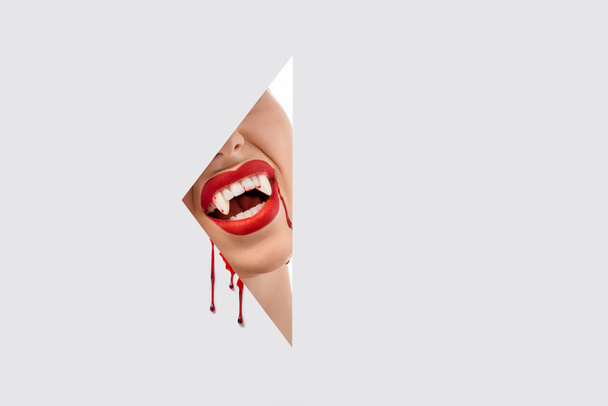 przycięte zdjęcie kobieta pokazując Zęby wampira przez otwór na białym - Zdjęcie, obraz