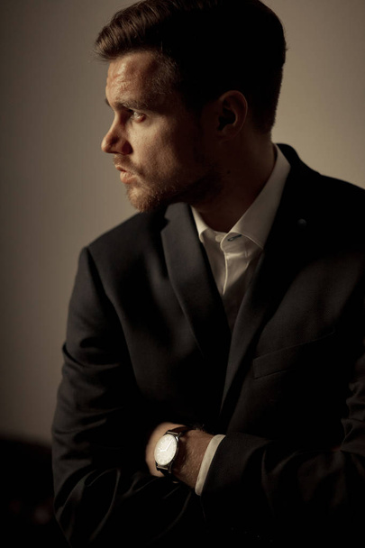 Retrato de un joven empresario con traje negro y camisa blanca sobre fondo marrón
. - Foto, Imagen