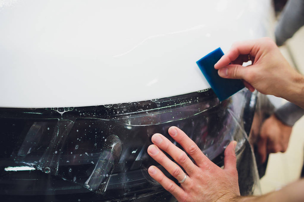 Transparent film, car paint protection, wrapping specialis. Car detailing. Selective focus. - Foto, Bild
