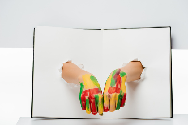 colpo ritagliato di mani femminili in vernice attraverso buchi su bianco
   - Foto, immagini