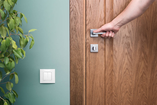 Open the door. Hand on door handle. Close - up elements of the interior of a beautiful apartment. The white switch on the green wall. Houseplan - Φωτογραφία, εικόνα