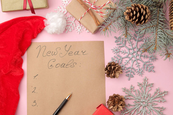 Νέους στόχους χρόνια 2019. Κείμενο σε ένα κομμάτι χαρτί με ένα πρωτοχρονιάτικο διακόσμηση και ένα στυλό πάνω σε ένα λαμπερό ροζ φόντο. - Φωτογραφία, εικόνα