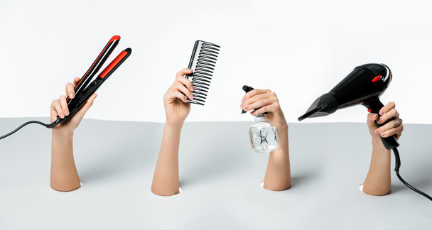 plan recadré de femmes tenant des outils de coiffure à travers des trous sur blanc
 - Photo, image