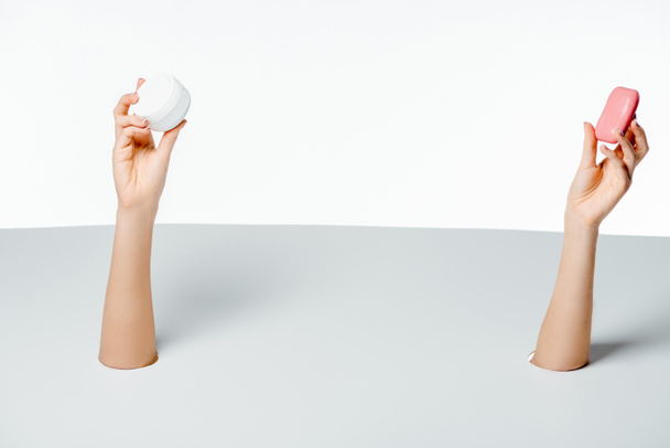 partial view of woman holding soap and cream through holes on white  - Fotoğraf, Görsel