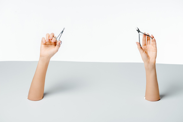 częściowy widok kobiety posiadające narzędzia manicure poprzez otwory na białym - Zdjęcie, obraz
