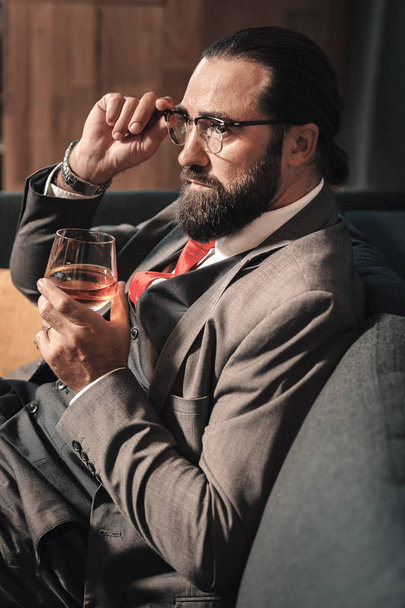 Bearded businessman wearing red tie drinking some cognac - Fotografie, Obrázek