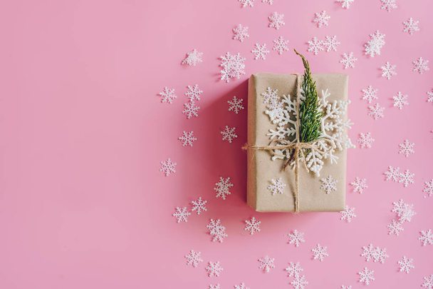 braune Geschenkschachtel auf rosa Hintergrund mit Weihnachtsdekoration. Minimal gestylte Urlaubskarte mit Kopierraum. - Foto, Bild