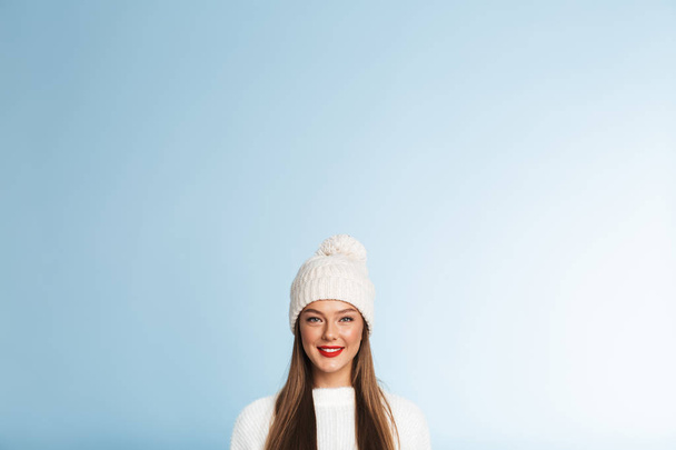 Image of a beautiful cute young woman wearing winter hat posing isolated over blue wall background. - Foto, afbeelding