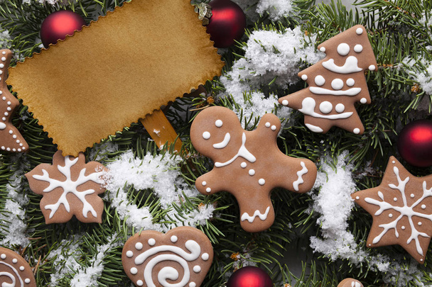 Blank paper card and Christmas gingerbread cookies on snow covered spruce branches - Foto, Imagem
