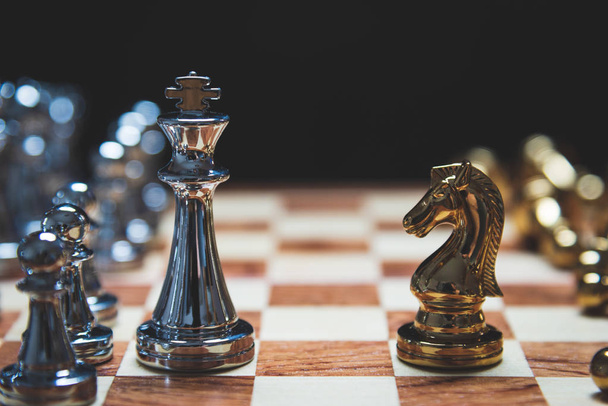 Stratégiai király erős vezetés és a gyenge vezetés ló egymással szemben a fa sakktábla. Üzleti marketing fogalmának verseny kereskedelmi partnerek taktika a fekete háttér - Fotó, kép