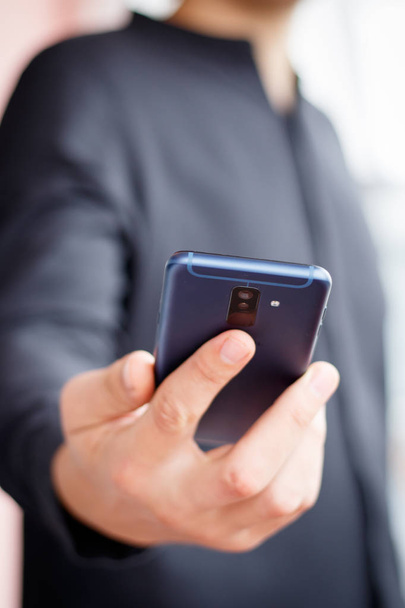 Mano maschile in possesso di uno smartphone cellulare e sms scrittura
 - Foto, immagini
