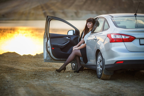 young happy beautiful big size model girl sit in her car on sunset. business woman resting after a hard day's work - 写真・画像