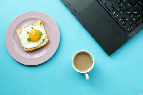  breakfast and laptop on blue background. - Photo, Image