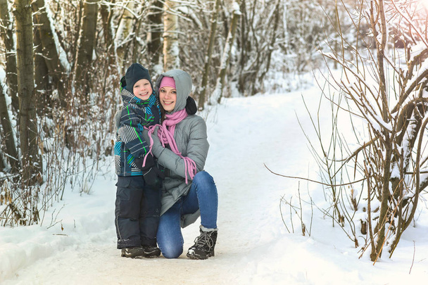 Happy smiling mother and son have a hug in winter forest. - Foto, Imagem