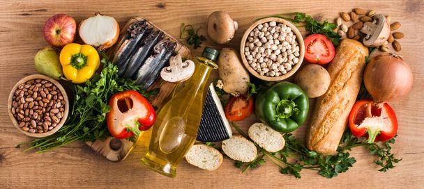 Alimentación saludable. Dieta mediterránea. Frutas, verduras, granos, frutos secos, aceite de oliva y pescado sobre una mesa de madera. Vista panorámica
 - Foto, imagen