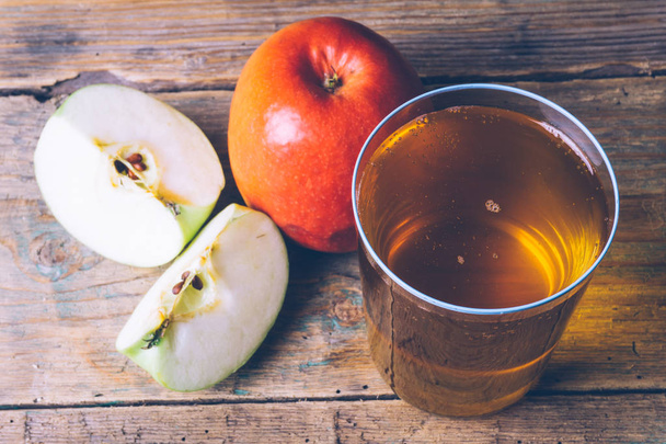 Cold apple cider or apple juice with fresh apples on a wooden background. Autumn drinks. Autumn mood. - Photo, Image