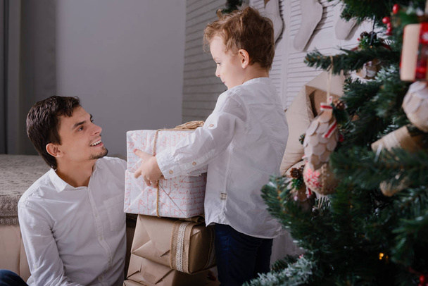 padre e hijo con regalos cerca de un árbol de Navidad
 - Foto, imagen