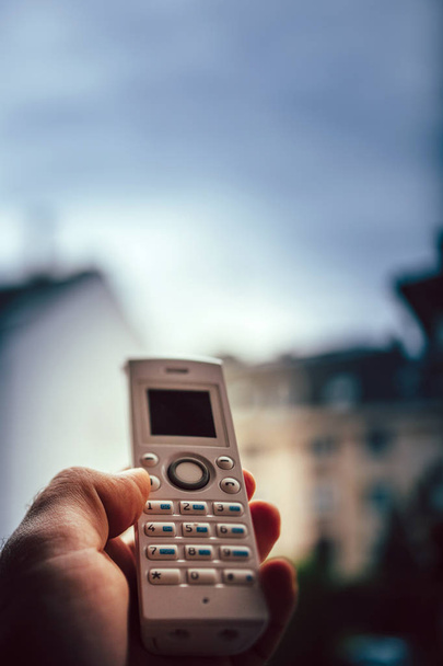 Homem mão segurando telefone sem fio chamando escritório em casa
 - Foto, Imagem