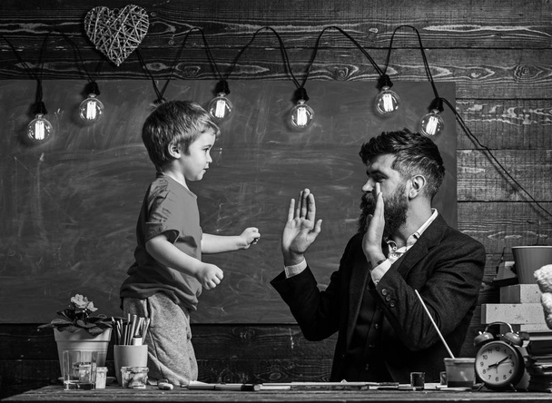 Art lesson concept. Child cheerful and teacher have fun during drawing. Talented artist spend time with son. Teacher with beard, father teaches son to draw in classroom, chalkboard on background - Φωτογραφία, εικόνα