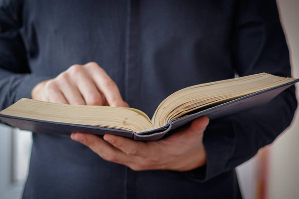 Hands folded in prayer on a Holy Bible in church concept for faith, spirtuality and religion - Fotografie, Obrázek
