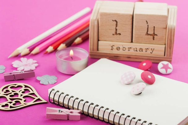 rosa Arbeitstisch mit Valentinsobjekten, Kalender und brennender Kerze - Foto, Bild