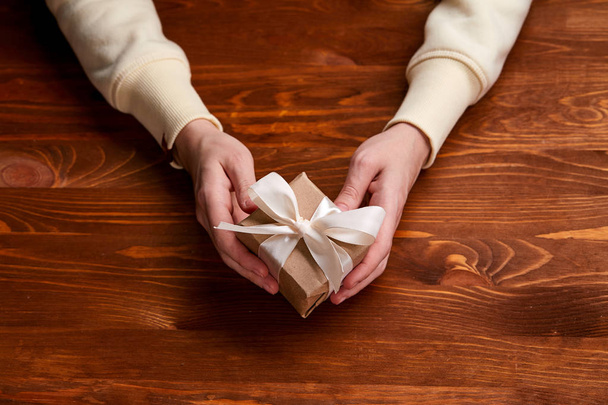 руки, що тримають подарункову коробку ремесел, крупним планом
  - Фото, зображення