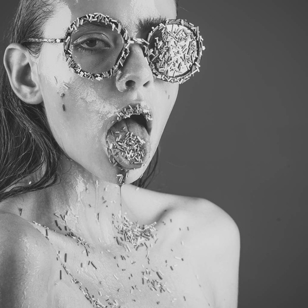 Young woman with sprinkles makeup. woman in fashionable glasses with sprinkles on tongue and lips. - Zdjęcie, obraz