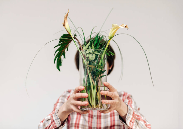 Woman holding in front of her face flower vase with dead plants - 写真・画像
