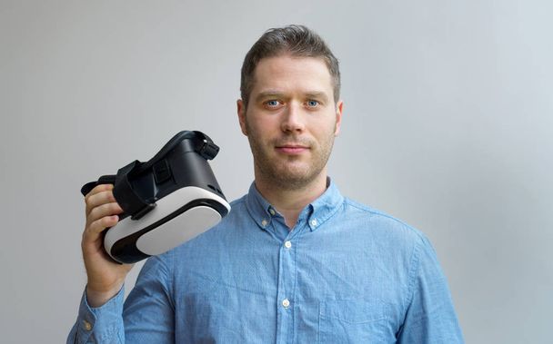 Handsome man holding virtual reality goggles. Space for your text. - Photo, Image