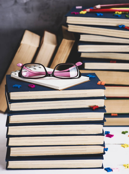 stos książek w niebieskiej okładce, różowe okulary na górze, vintage tonizujący - Zdjęcie, obraz