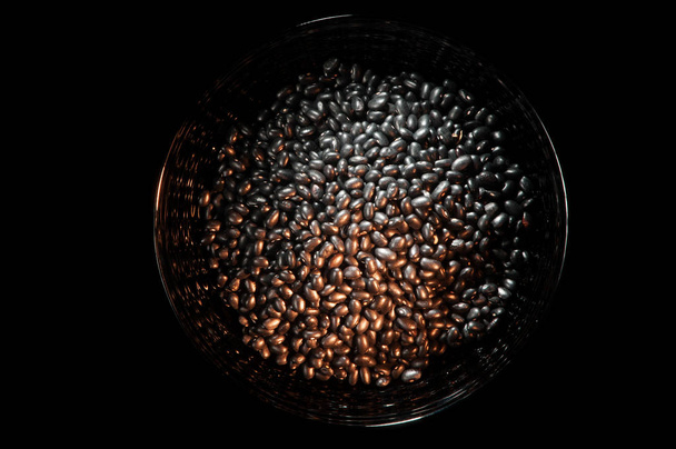 Bowl filled with black beans on a black background - Fotó, kép