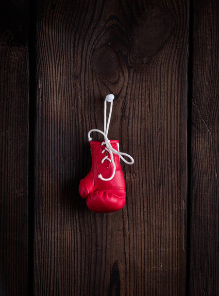 one leather red boxing glove with laces on a brown wooden background - Φωτογραφία, εικόνα