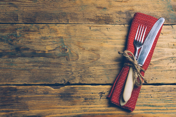 Holiday Christmas food background concept. Christmas or New Year table with a set of cutlery knife and fork on a red napkin with Christmas decorations. Old rustic vintage wood background. Copy space. - Photo, Image