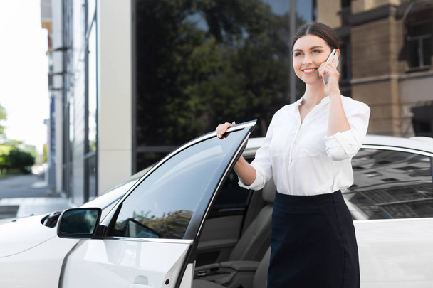 Arabanın kapısını açarak telefonda konuşurken işkadını - Fotoğraf, Görsel