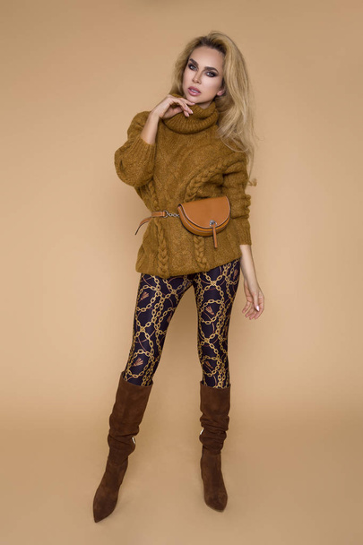 Красива жіноча модель в осінньо-зимовому одязі, на бежевому тлі в студії
 - Фото, зображення