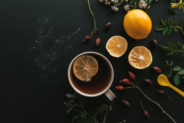 Rose hip herbal tea flt lay top view with slice of lemon on wooden table - Fotó, kép