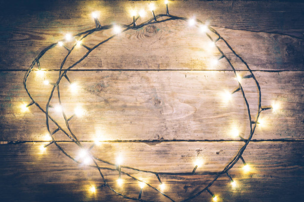 Christmas lights frame. Christmas wooden rustic background with (decorated) christmas lights. Copy space. Top view. Christmas mood, comfort. - Photo, Image