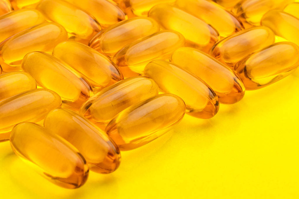 Omega 3 capsules from fish oil on a yellow background. Texture, pattern. Copy space  - Φωτογραφία, εικόνα