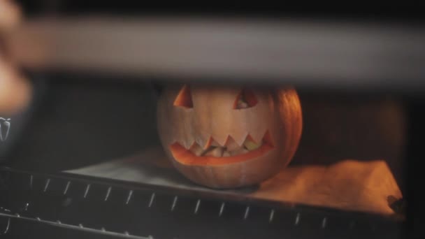 Carved pumpkin on Halloween party is baked in the oven stuffed with apples. Close-up - Footage, Video