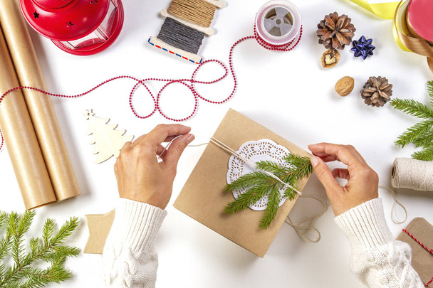 Weihnachtsgeschenkverpackung. Frauenhände packen Weihnachtsgeschenke auf weißem Tisch - Foto, Bild