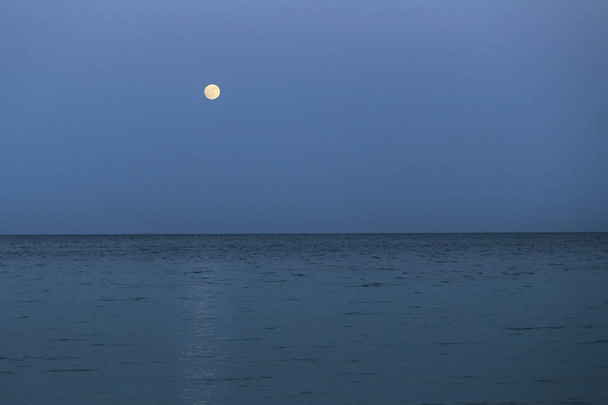 Big full moon is rising above the sea at dusk. - Photo, Image