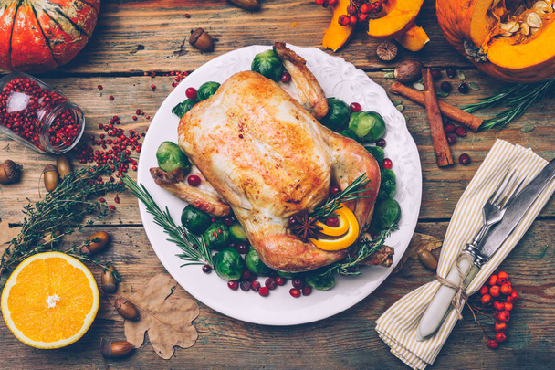 Ημέρα των Ευχαριστιών ψητό κοτόπουλο με λαχανάκια Βρυξελλών και μπαχαρικά σε ένα ρουστίκ ξύλινο τραπέζι. Ημέρα των ευχαριστιών δείπνο ή πτώση δείπνο έννοια φόντο με φθινοπωρινά φύλλα. Ευχαριστιών πίνακα ρύθμιση φόντο. - Φωτογραφία, εικόνα