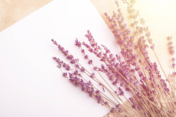 Mock up of blank sheet and branches of lavender on the table. Place for your design. View from above. Toning - Fotó, kép