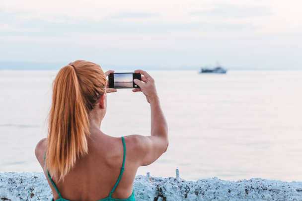 Mladá žena turistické pořizování fotografií s smartphone u moře - Fotografie, Obrázek