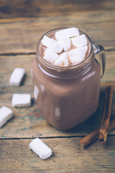 Tasse heißen Kakao oder heiße Schokolade mit Marshmallows und Zimtstangen auf Holzuntergrund. Winterstimmung. - Foto, Bild