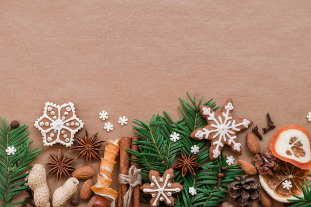 Christmas decoration with spices and cookies in the shape of snowflakes on dark brown paper background. Top view. - Foto, afbeelding