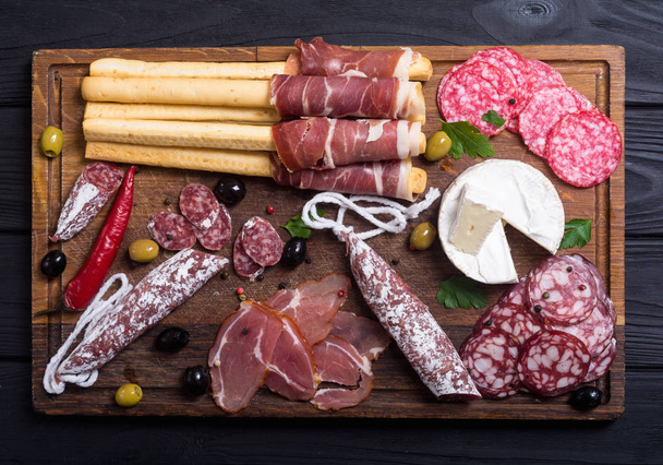 Set of sausages ( ham , salami , jamon ) and olives on wooden board - Foto, Bild