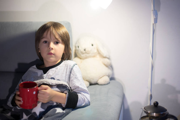 Sick child boy lying on the sofa with a fever, resting at home - Photo, image