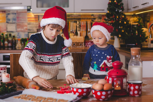 Sweet toddler child and his older brother, boys, helping mommy preparing Christmas cookies at home in kitchen - Foto, immagini